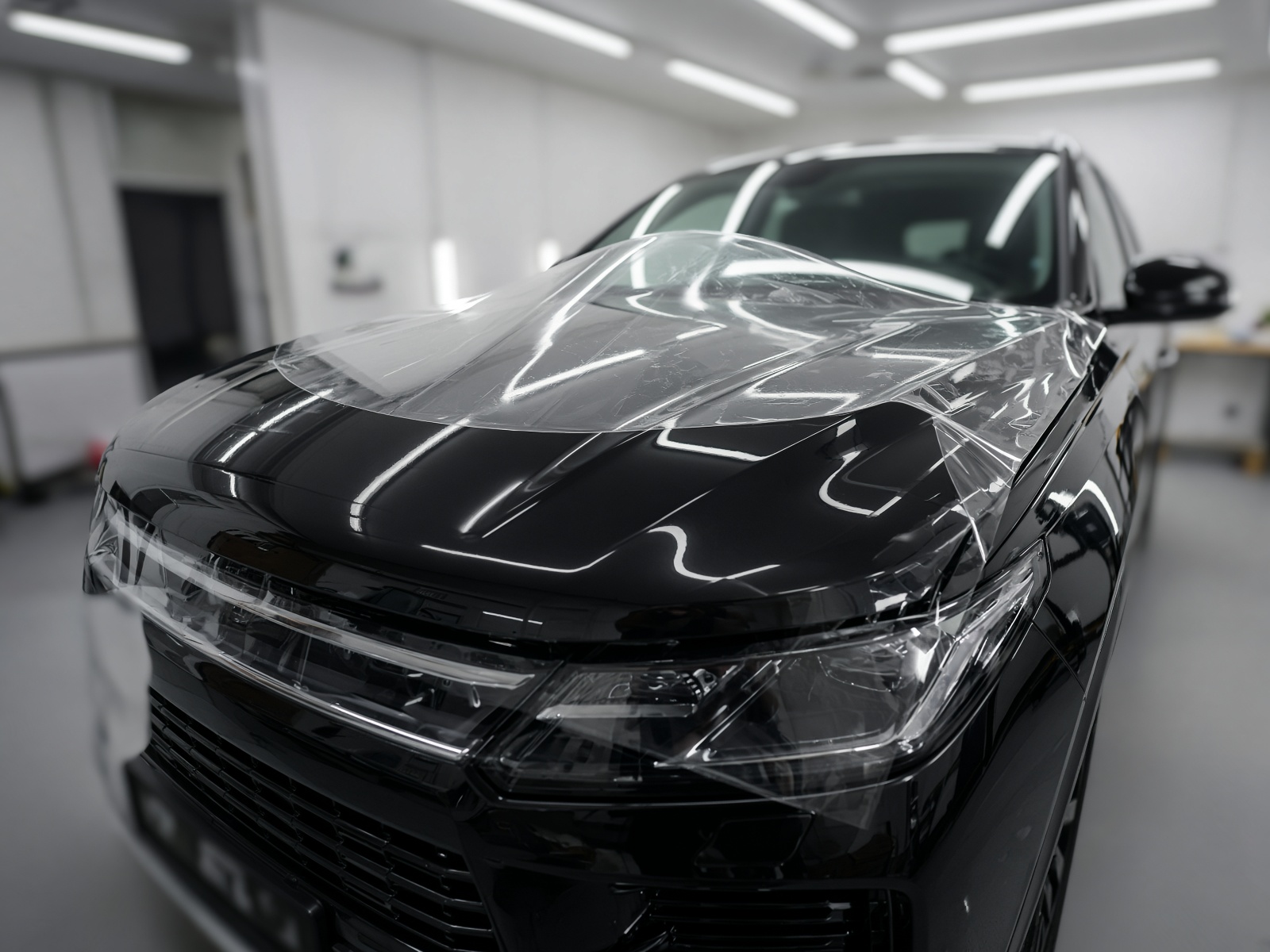 Clear paint protection film being aligned on a vehicle hood